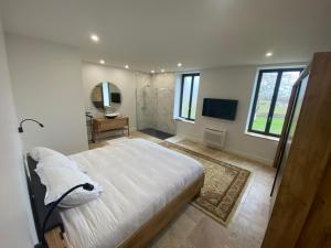 1 dormitorio con 1 cama blanca grande y TV en Le domaine Reine Sully, en Saint-Quentin-de-Caplong