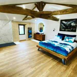 1 dormitorio con 1 cama grande y suelo de madera en Le domaine Reine Sully, en Saint-Quentin-de-Caplong