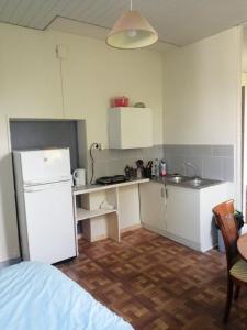 a kitchen with a white refrigerator and a sink at Au calme, devant le port, studio indépendant in Lere