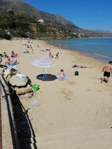- un groupe de personnes sur une plage avec un parasol dans l'établissement Accussì, à Alcamo Marina
