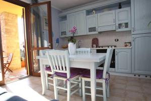 a white kitchen with a white table and chairs at Casa Mirella - Toscolano Maderno in Toscolano Maderno