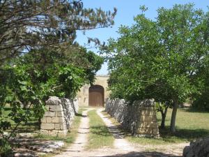une porte menant à un mur en pierre avec des arbres et un chemin dans l'établissement Masseria Copertini, à Vernole