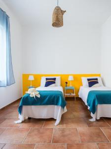 two beds in a room with blue and yellow at VENTO DI SCIROCCO CASA VACANZE A POCHI METRI DAL MARE in Santa Flavia