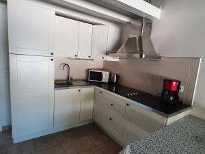 a kitchen with white cabinets and a sink and a microwave at La Bastide Bleue in Anduze