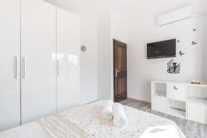 a white bedroom with a bed and a tv at Holiday home Giovanni in Solin