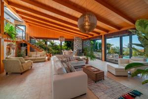 ein Wohnzimmer mit Sofas, Tischen und Fenstern in der Unterkunft OurMadeira - Garden Paradise, stunning in Calheta
