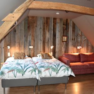 twee bedden in een kamer met een houten muur bij B&B Stefans Pottery in Poperinge