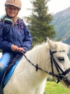 a young girl riding on a white horse at Alpengasthof Gaislach Alm in Sölden