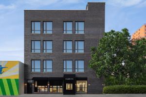 a brick building with windows and a tree at The Baltic Hotel in Brooklyn