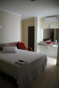 a bedroom with a large white bed and a kitchen at Colorado Plaza Hotel in Rio Verde