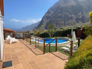 un patio con piscina y una montaña en el fondo en Villamocanes en Frontera