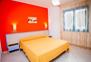 a bedroom with a yellow bed and an orange wall at Terra del Sole in Favignana