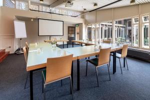 una sala de conferencias con una mesa grande y sillas en Stayokay Hostel Apeldoorn, en Apeldoorn