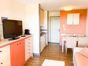 a living room with a television and a kitchen with a couch at Residence Cap Esterel Babou in Saint-Raphaël