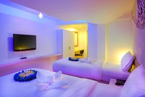 a hotel room with two beds and a flat screen tv at Holidays Home in Pattaya South