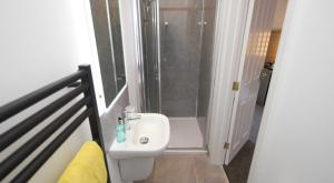W łazience znajduje się prysznic i biała umywalka. w obiekcie Guest Rooms @ 128 w mieście Portrush