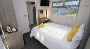 a bedroom with a white bed with yellow pillows and a window at Guest Rooms @ 128 in Portrush