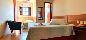 a bedroom with a bed with a mirror and a chair at Colorado Plaza Hotel in Rio Verde