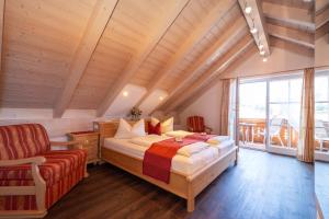 a bedroom with a bed and a chair at Boutique Hotel Angerer in Murnau am Staffelsee