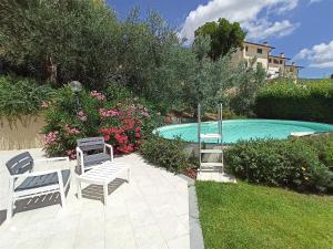 a swimming pool with two white benches and flowers at La Solaria in Carmignano