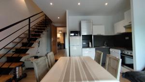 eine Küche und ein Esszimmer mit einem Tisch und einer Treppe in der Unterkunft Domaine Ravy-Lilas in Saint-Symphorien-sur-Saône