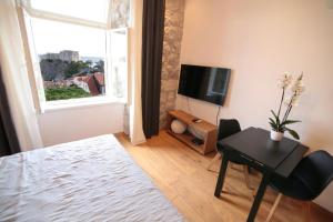 Una sala de estar con una mesa y un televisor. en Apartments Cava Dubrovnik, en Dubrovnik