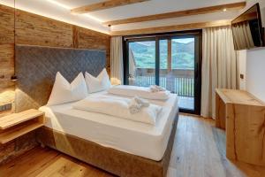 ein Schlafzimmer mit einem großen Bett und einem großen Fenster in der Unterkunft Hotel Residence Gasser in Villanders