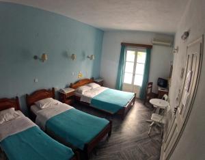 a room with three beds and a window at Damias Village in Parikia