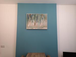 een schilderij op een blauwe muur met een houten tafel bij Mandela House Apartments in Kirkcaldy