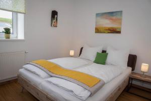 um quarto com uma cama grande com lençóis brancos e amarelos em WeinApart im Winzerschlössl em Eisenstadt