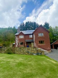 a red brick house with a stone wall at Laurel Bank in Abbey-Cwmhir