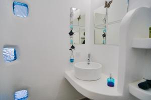 Kalimera Appartament في مدينة ميكونوس: حمام أبيض مع حوض ومرآة