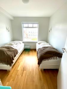 two beds in a room with a window at Day Dream R1 Townhall Studio in Akureyri