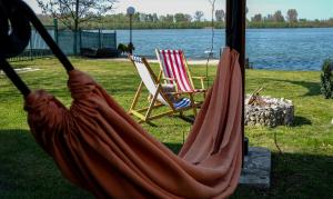 a hammock with two chairs and a body of water at Dunavska Kuća in Smederevo