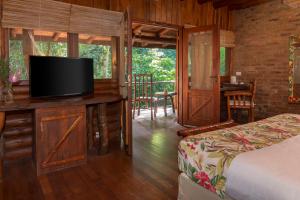 a bedroom with a bed and a flat screen tv at La Aldea De La Selva Lodge in Puerto Iguazú