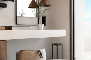 a white counter with a mirror and a chair at Domes White Coast Milos, Adults Only - Small Luxury Hotels of the World in Mytakas