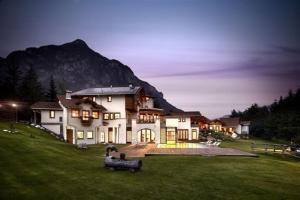 una casa grande en un campo con una montaña en Castelir Suite Hotel, en Panchia