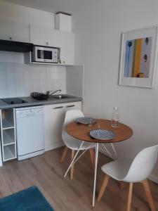 cocina con mesa de madera y electrodomésticos blancos en Le cosy de Saint Jean, en Saint-Jean