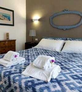 ein blau-weißes Bett mit Handtüchern und Blumen darauf in der Unterkunft IL LEUDO in Lavagna