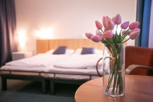 a vase of flowers sitting on a table with a bed at Penzion Hotelu Central in Dvůr Králové nad Labem