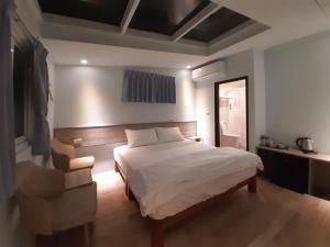 a bedroom with a white bed and a chair at Yueli Homestay in Magong