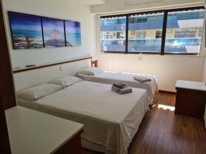 two beds in a room with two windows at Flat Pasárgada 712 - apt com vista para a Praia da Costa, academia moderna, piscinas panorâmicas, minimercado e lavanderia in Vila Velha +85 photos