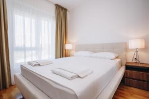 a bedroom with a white bed with two towels on it at Status-M Apartments 176 in Bečići +21 photos