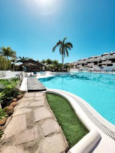 een zwembad in een resort met palmbomen bij Suite Adeje Paradise with private jacuzzi in Adeje