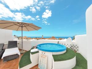 une terrasse avec un bain à remous et un parasol dans l'établissement Suite Adeje Paradise with private jacuzzi, à Adeje