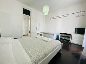 a white bedroom with a bed and a television at Liolà Palermo in Palermo