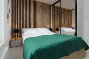 a bedroom with a large bed with a green blanket at Apartamenty Forest - Nadmorskie Tarasy D409 in Kołobrzeg +37 photos