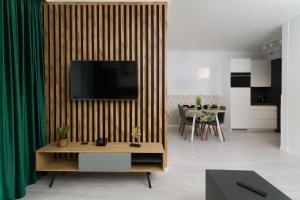 a living room with a television on a wooden wall at Apartamenty Forest - Nadmorskie Tarasy D409 in Kołobrzeg