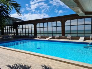 a swimming pool with a view of the ocean at Flat Pasárgada 712 - apt com vista para a Praia da Costa, academia moderna, piscinas panorâmicas, minimercado e lavanderia in Vila Velha