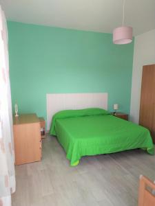 Schlafzimmer mit grünem Bett und blauen Wänden in der Unterkunft Goethe Paestum House in Paestum